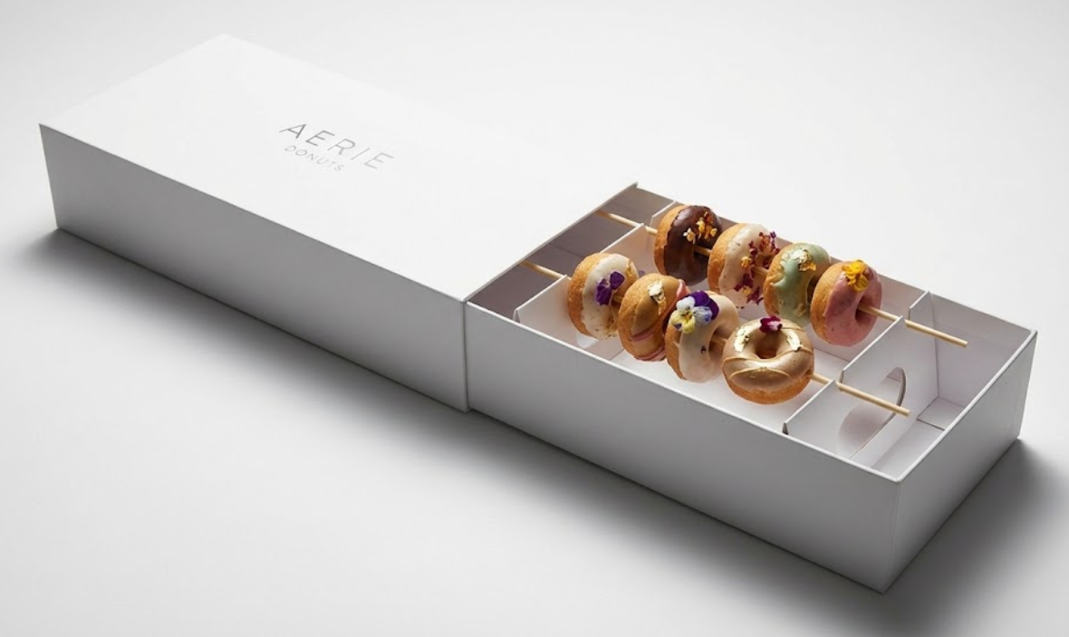 Creative rectangular gift box featuring a custom cardboard insert that suspends mini donut skewers in mid-air to protect toppings during transport.